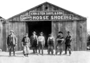 Blacksmiths outside a horse shoeing barn