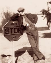 A man leaning up against a stop sign